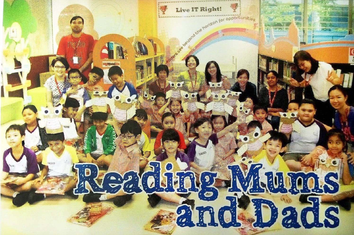 Group of children and adults in a library holding owl crafts, with text Reading Mums and Dads overlaid.
