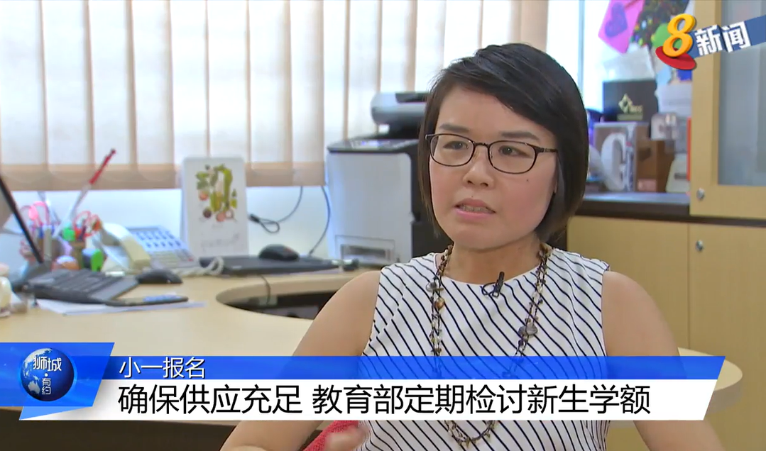 A woman with glasses and short hair sits in an office during a Chinese news broadcast with on-screen text.