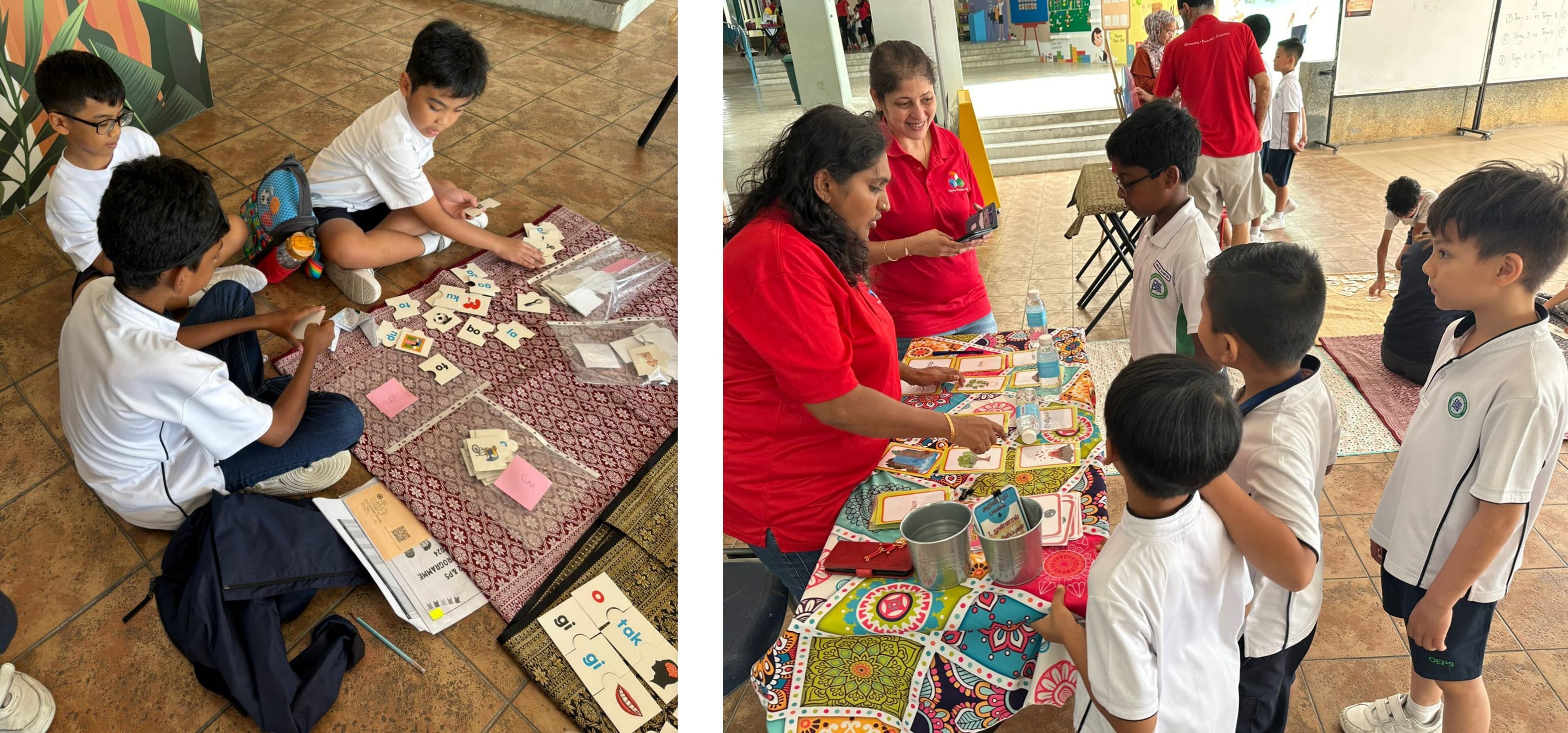 Students in white uniforms do word card activities on the floor and at a colorful table with two adults in red shirts.