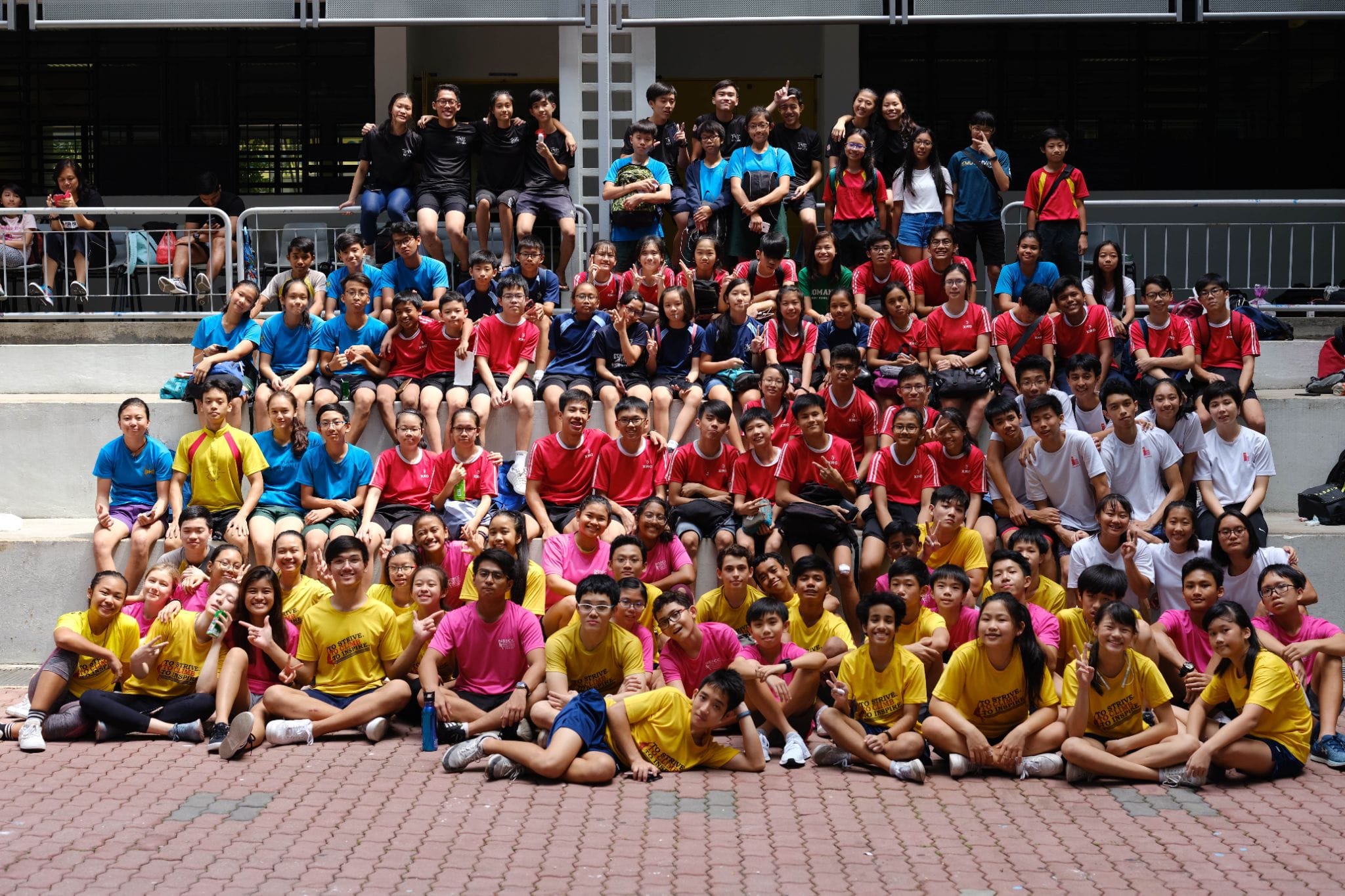 Large group of students in colorful shirts posing on outdoor steps for a group photo.