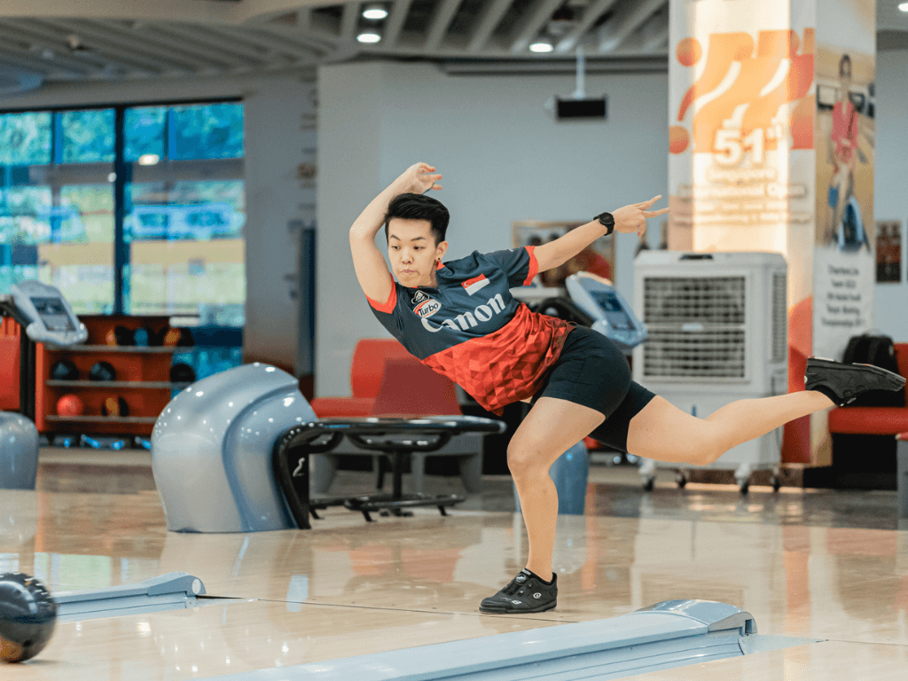 Woman bowling with a ball in her hand, preparing for a throw at a bowling alley