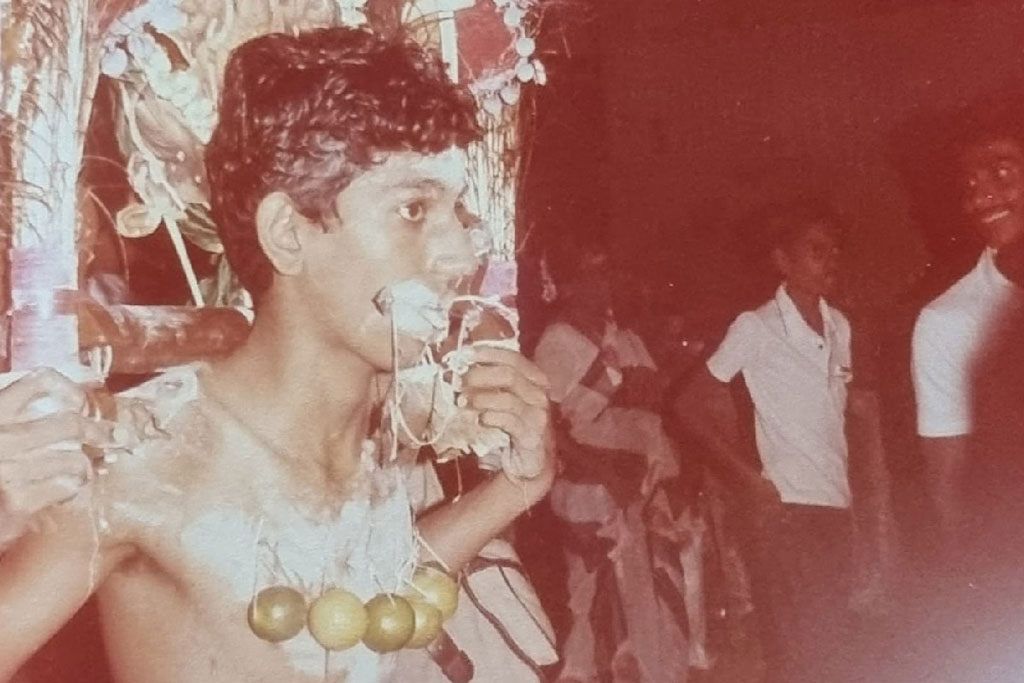 Young man with cheek and chest piercings carrying kavadi during a Thaipusam procession.